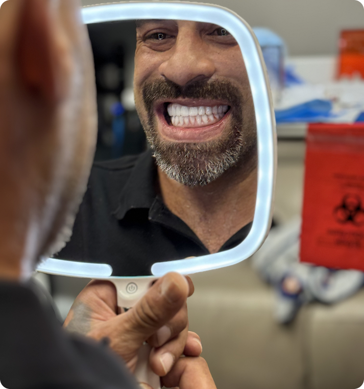 Man smiling at his new teeth in a mirror